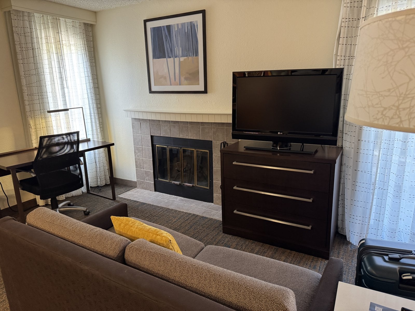 Residence Inn by Marriottのスイートのリビングスペース。ソファ、デスク、暖炉があります。