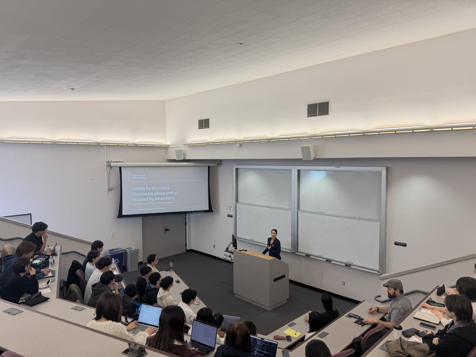 加州大學聖地牙哥分校研究所(GPS)的階梯教室。學生們打開筆記型電腦並排而坐,講師在前方講台上授課。