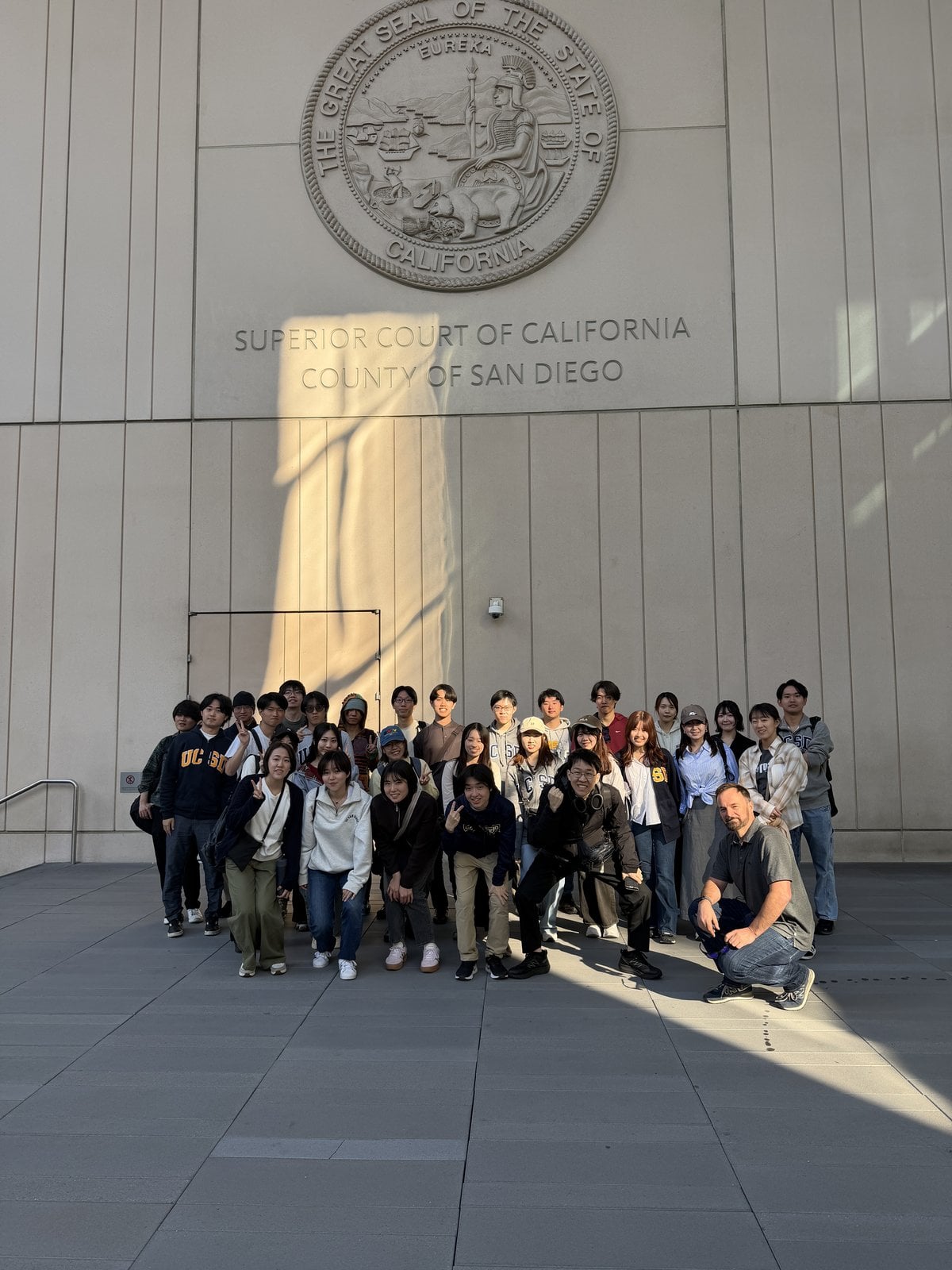 Participants gathered outside the San Diego Superior Court, below the carved Great Seal of the State of California.